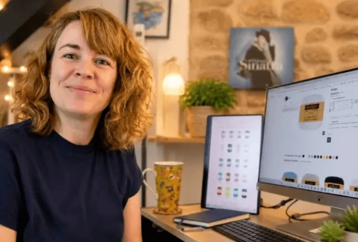 Aurélie smiling at her desk, beside a tablet, a computer screen and a flowered mug